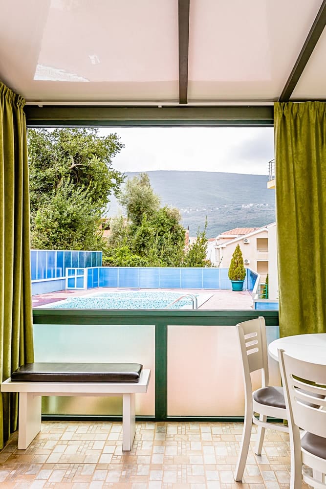 Balcony with dining area and views of the pool and mountains in an apartment, Đenovići, Montenegro.