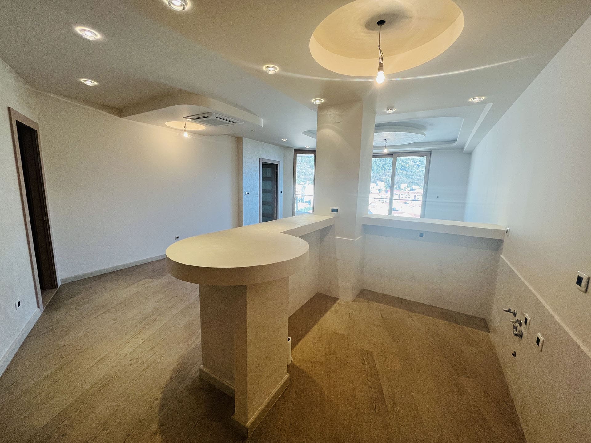 Modern kitchen in an apartment in Budva, Montenegro: a breakfast bar, designer ceiling, and mountain view.