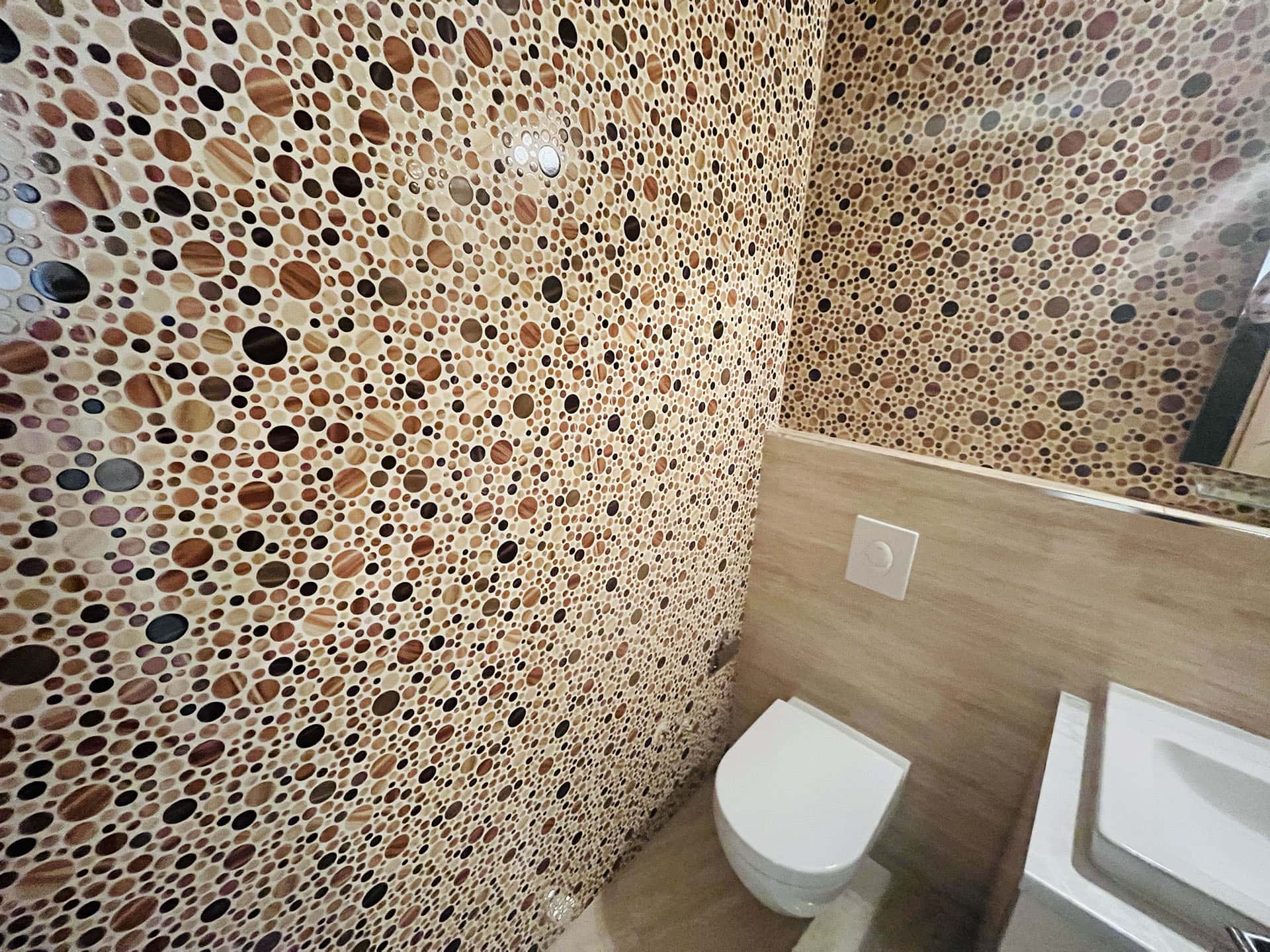 Modern bathroom in an apartment in Budva, Montenegro: walls finished with mosaic tiles featuring a circular pattern.