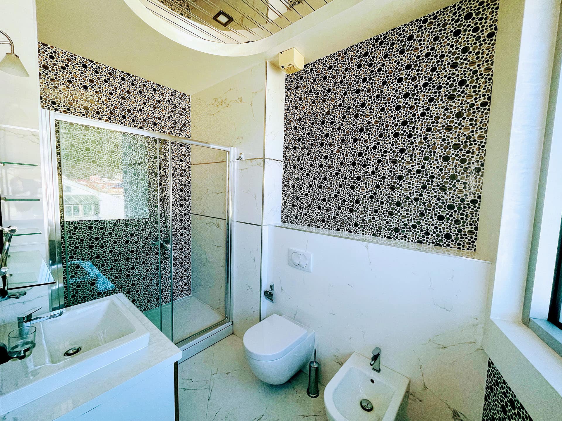Modern bathroom in an apartment in Budva, Montenegro: shower cabin, mosaic tiles, and high-quality plumbing fixtures.