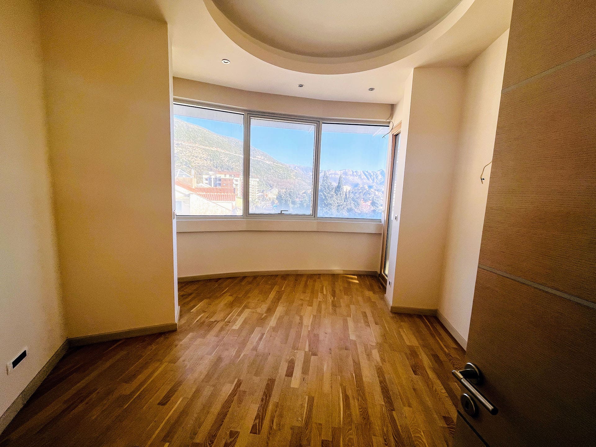 Bright living room with parquet flooring and panoramic mountain views in an apartment, Budva, Montenegro.