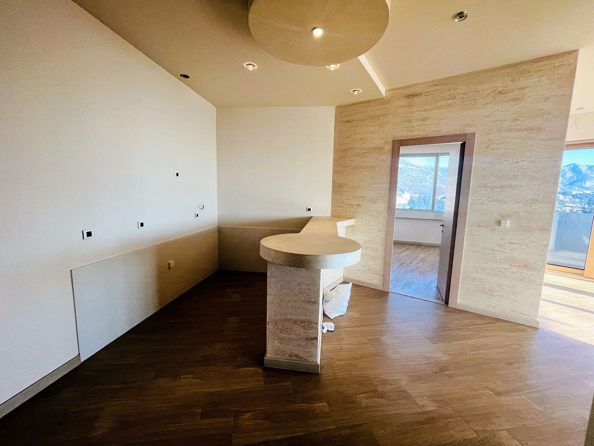 Living room interior with a bar counter and mountain views in a new apartment, Budva, Montenegro. Modern wall finishes.