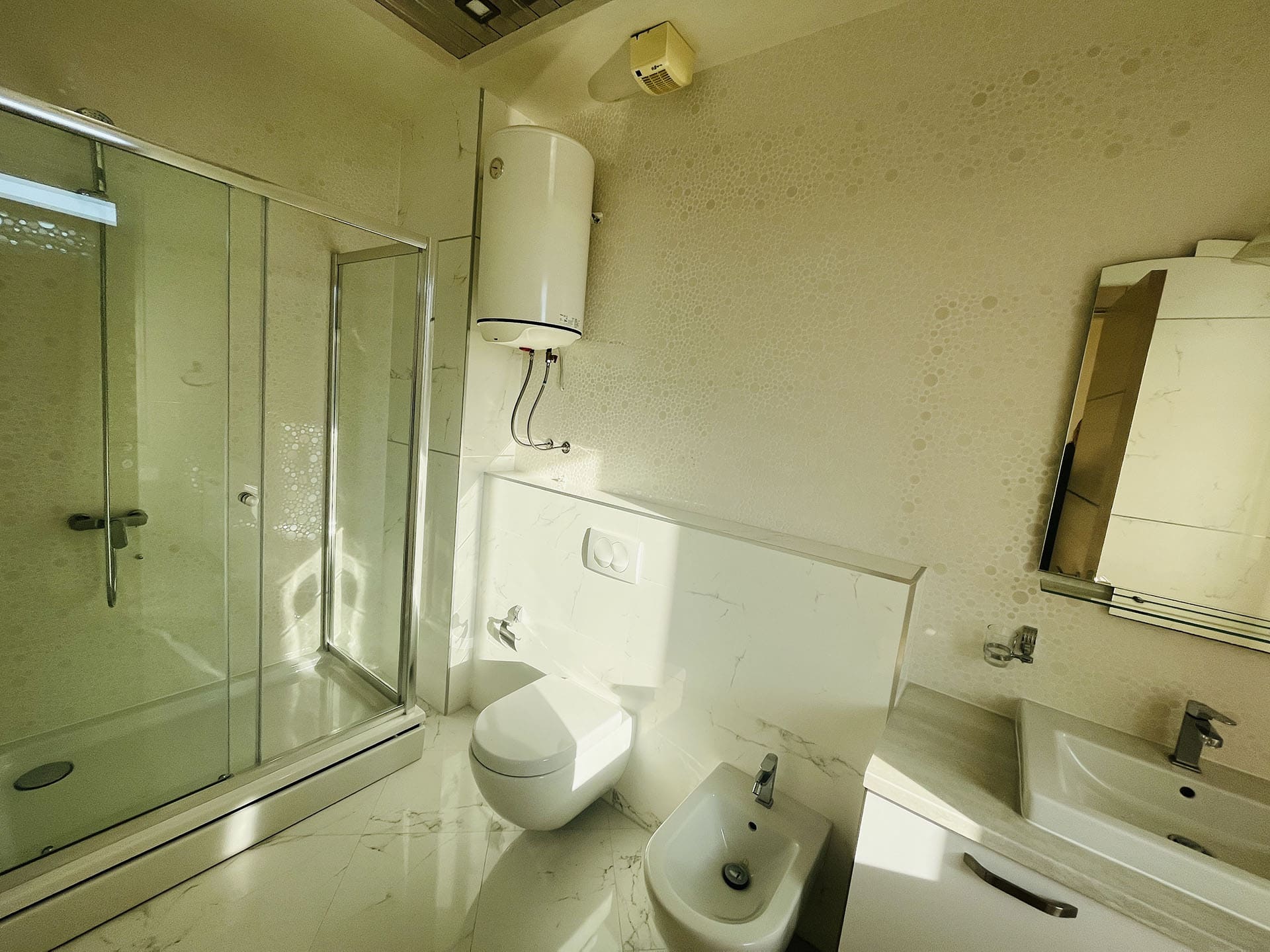 Modern bathroom with a shower cabin and bidet in an apartment in Budva, Montenegro: bright marble-style finish.