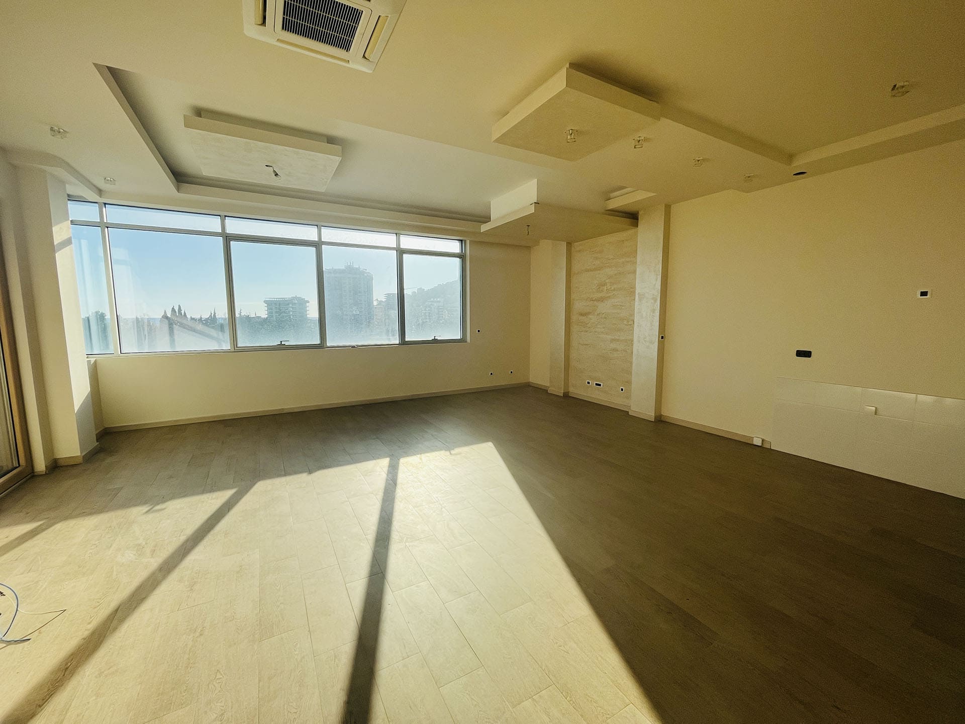 Spacious living room with panoramic windows in a new apartment in Budva, Montenegro: bright interior and high-quality finishes.