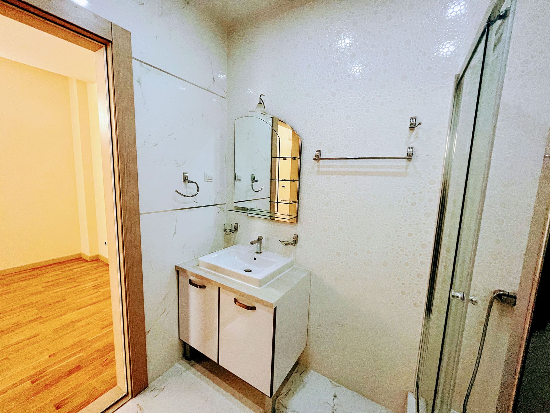 Modern bathroom with a shower cabin and light finishes in an apartment for sale in Budva, Montenegro.