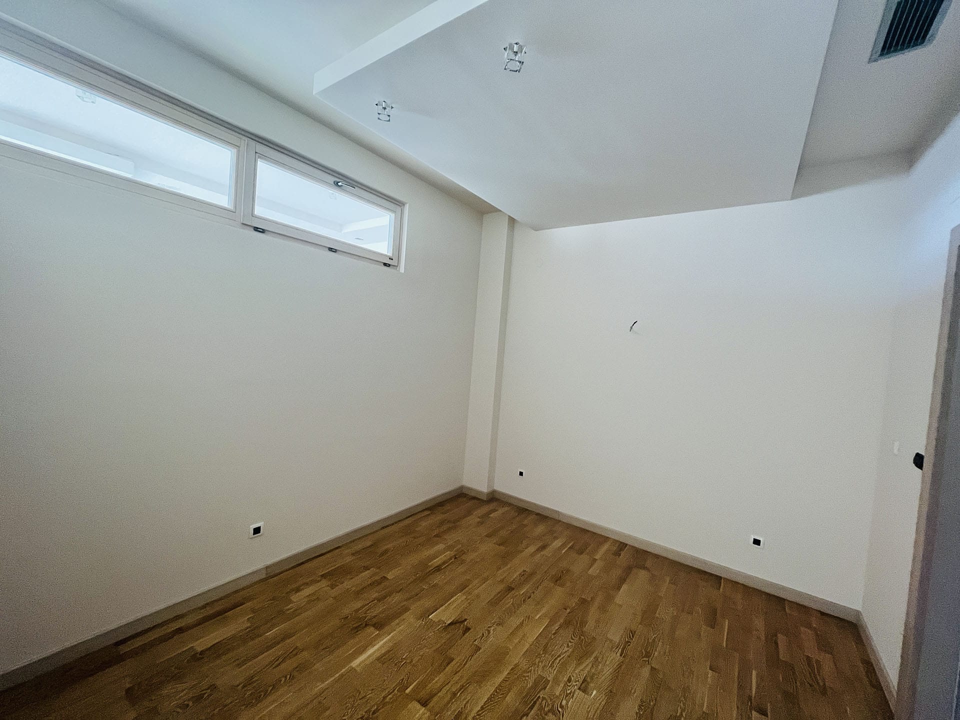 Bright bedroom with parquet flooring and built-in lighting in a new apartment in Budva, Montenegro.