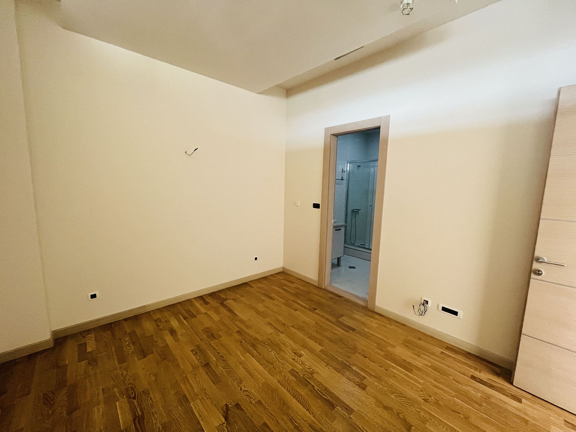 Bright bedroom with parquet flooring and access to the bathroom in an apartment, Budva, Montenegro.