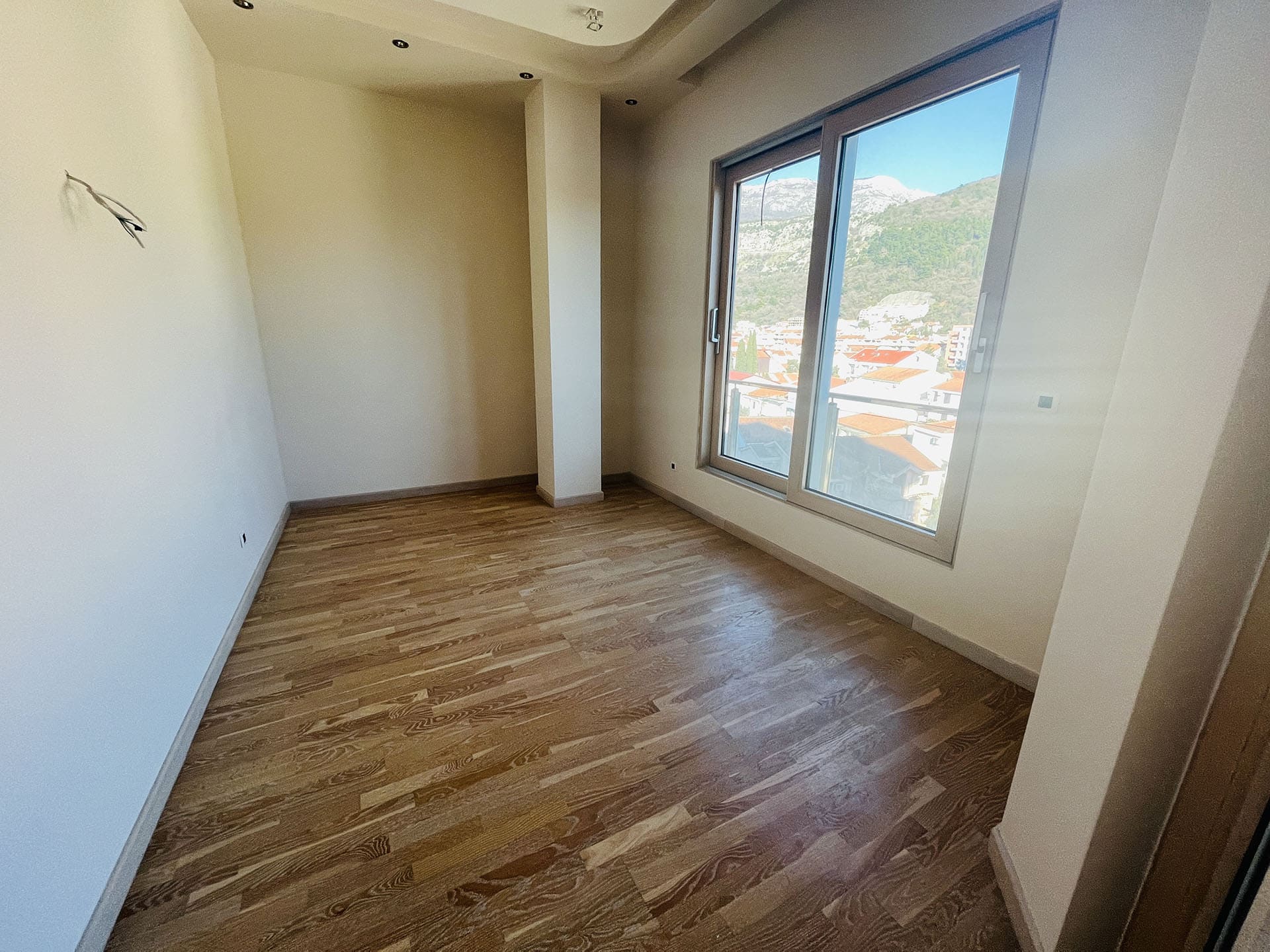 Bright bedroom with parquet flooring and panoramic views of the mountains and city in a new apartment, Budva, Montenegro.