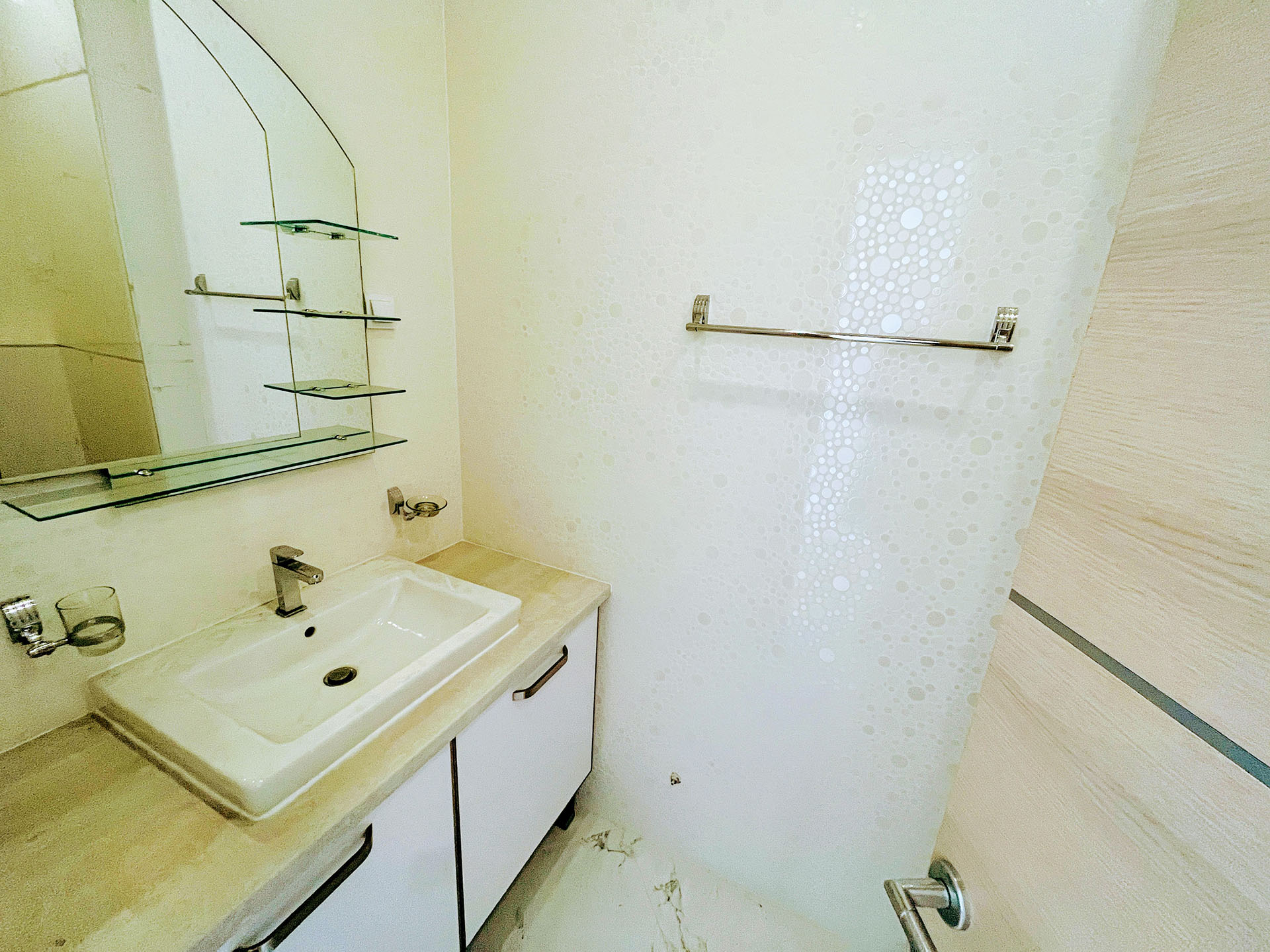 Bright bathroom in an apartment in Budva, Montenegro: white vanity with sink, mirror, and modern wall finishes.
