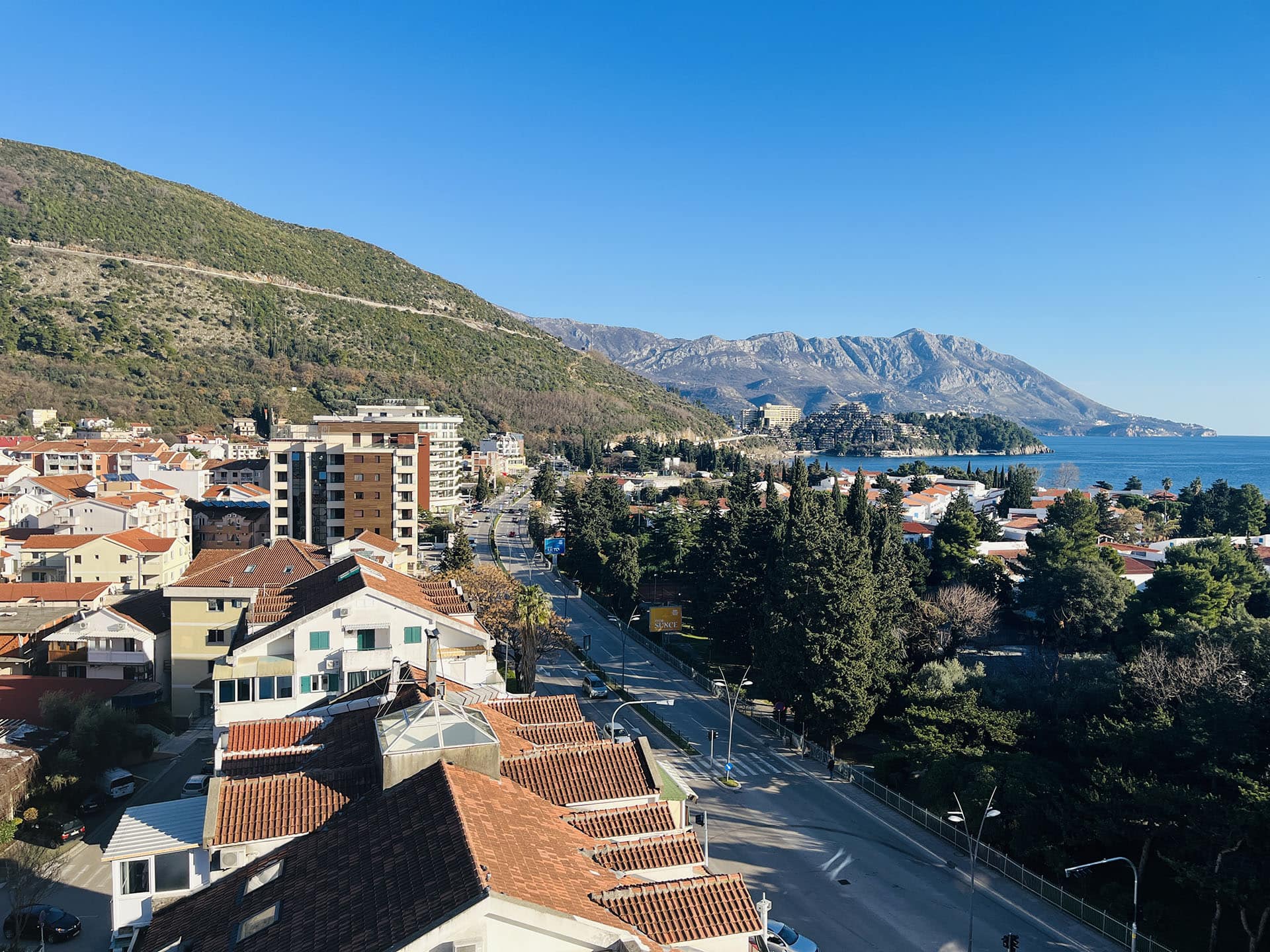 Panoramic view of Budva, the mountains, and the Adriatic Sea from an apartment in Montenegro, sunny day.