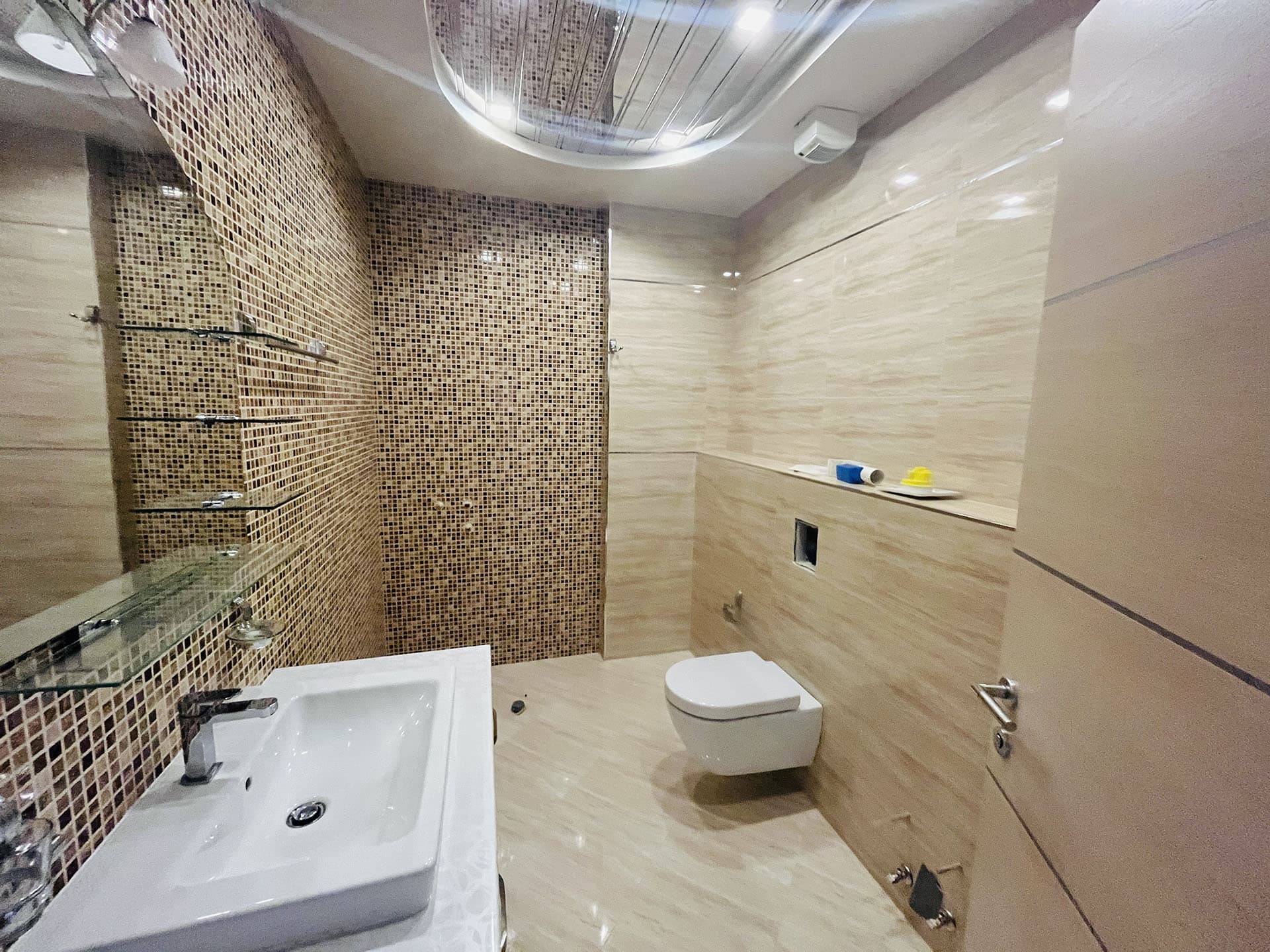 Modern bathroom with mosaic tiles and wall-mounted fixtures in an apartment, Budva, Montenegro.
