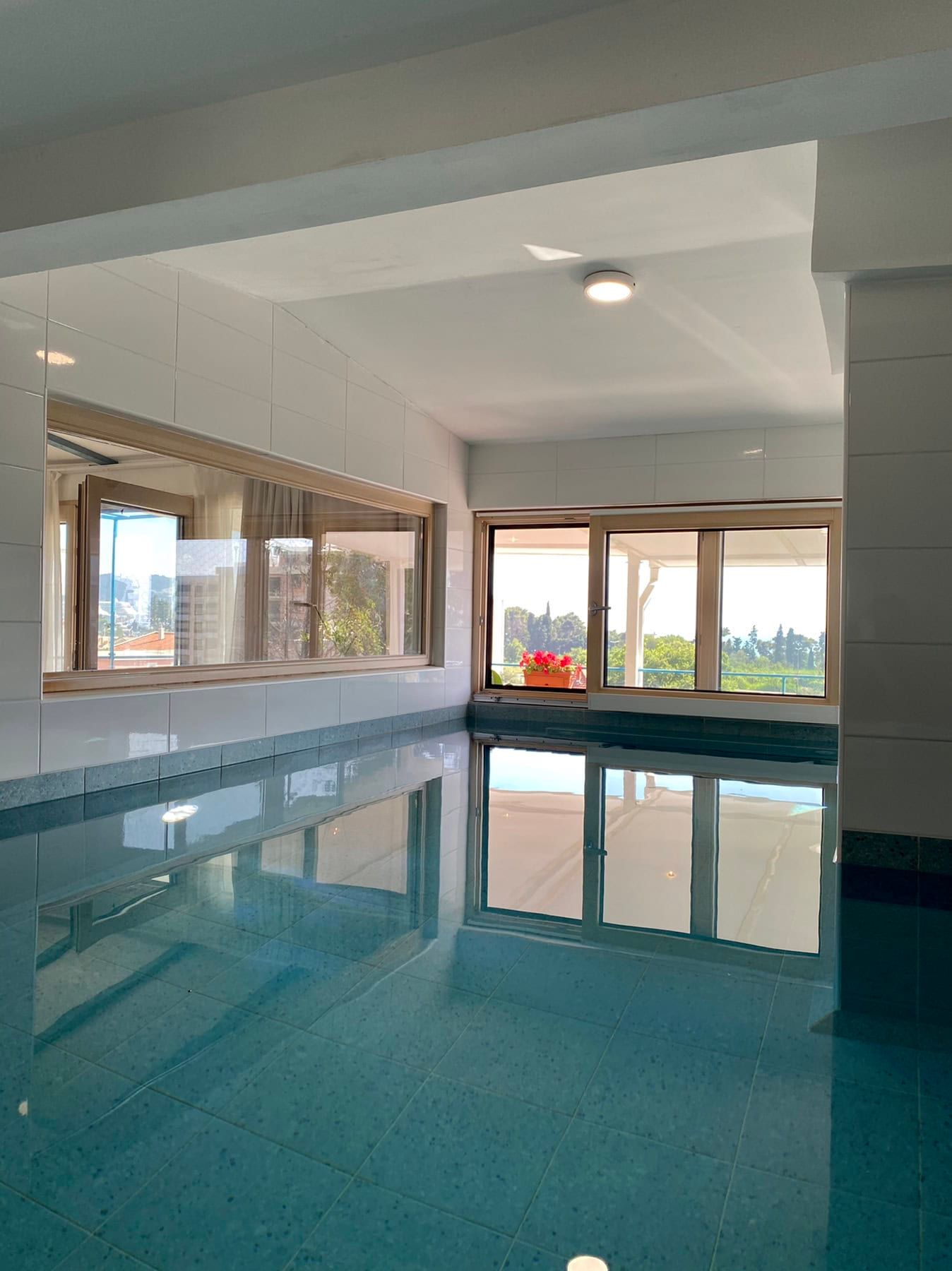 Indoor pool with panoramic windows and nature views in a house, Shushan, Montenegro. Tiled finish, bright interior.