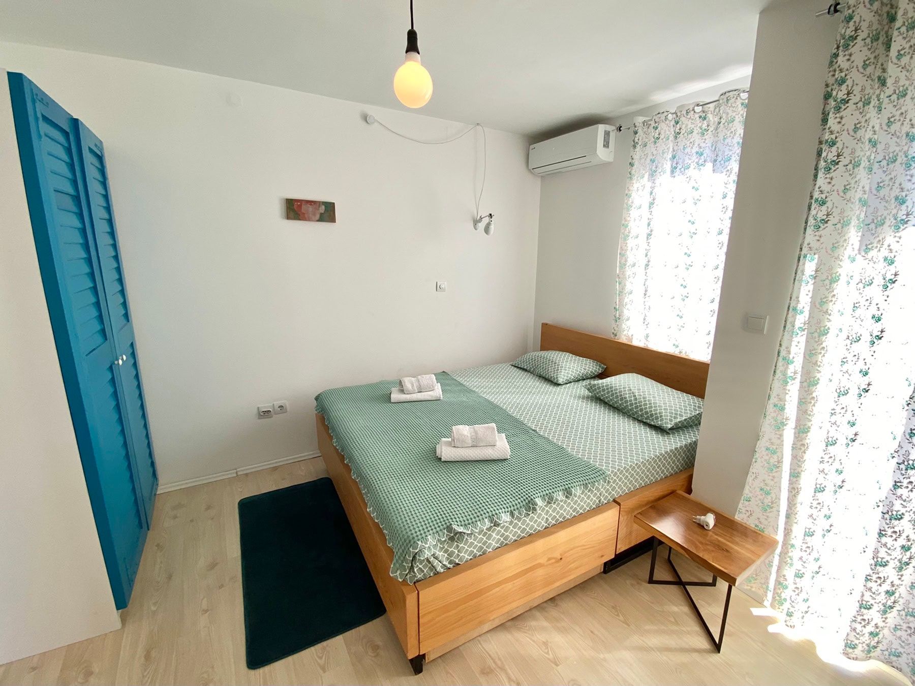 Cozy bedroom with a double bed and a blue wardrobe in a house, Shushan, Montenegro. Bright interior with air conditioning.