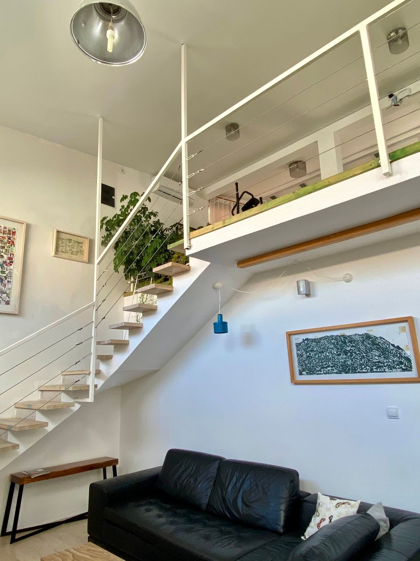 Living room with a split-level layout and a wooden staircase in a house, Shushan, Montenegro. Modern interior with a sofa.