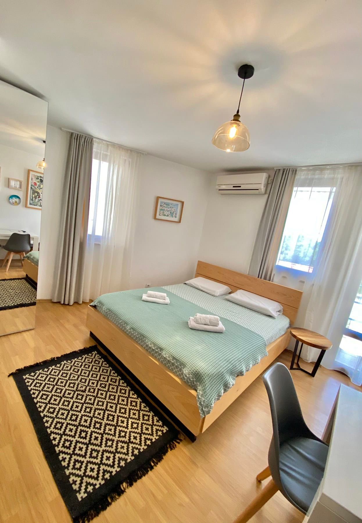 Bright bedroom with a double bed in a house in Shushan, Montenegro: modern furniture, parquet flooring, and a view from the window.