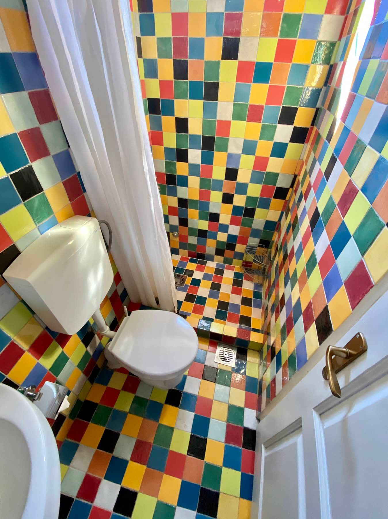 Bathroom with bright multicolored tiles in a house for sale in Shushan, Montenegro: shower and plumbing.