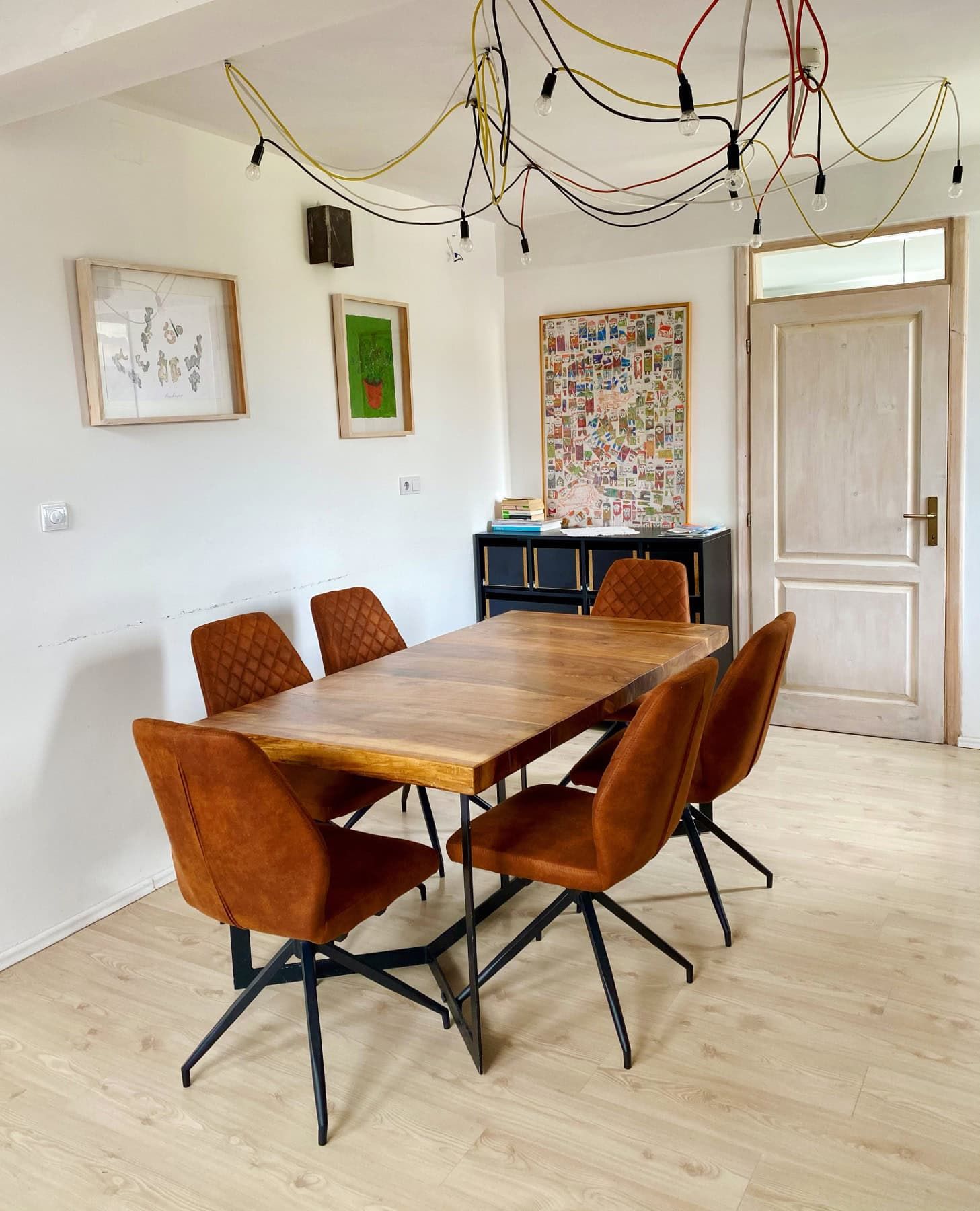 Dining area in a house in Shushan, Montenegro: wooden table, terracotta chairs, and a designer chandelier in the living room.