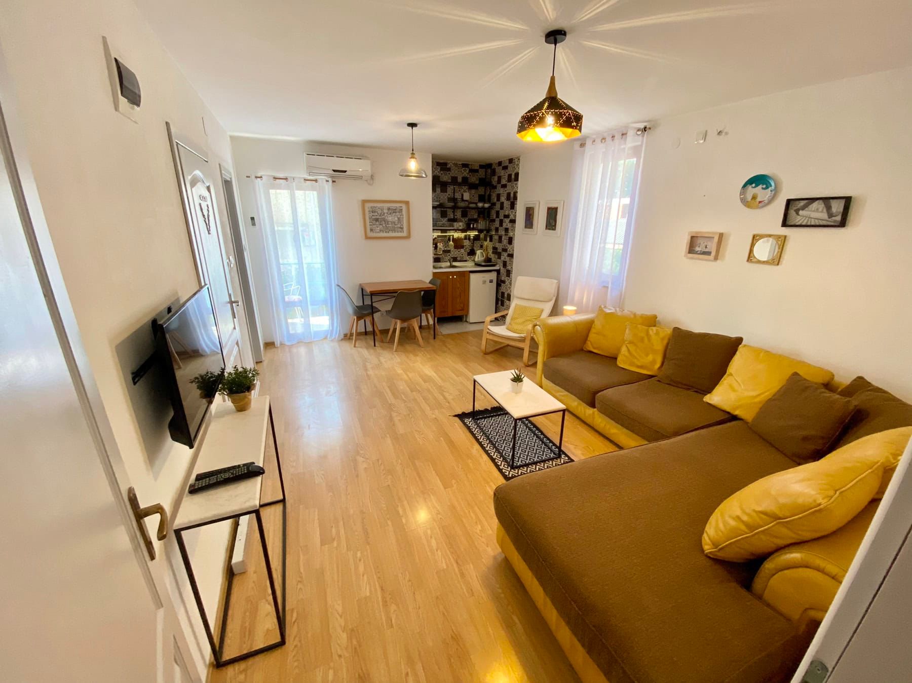 Living room with an L-shaped sofa and kitchen in a house in Shushan, Montenegro: bright interior, parquet flooring, and modern furniture.