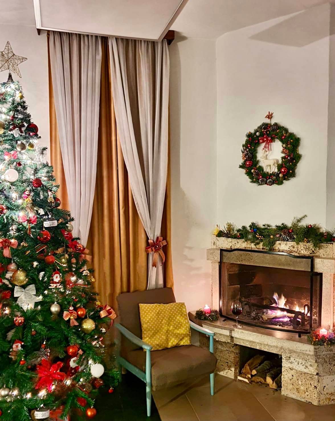 Cozy living room with a fireplace and Christmas tree in a house in Shushan, Montenegro: interior with an armchair and festive decor.