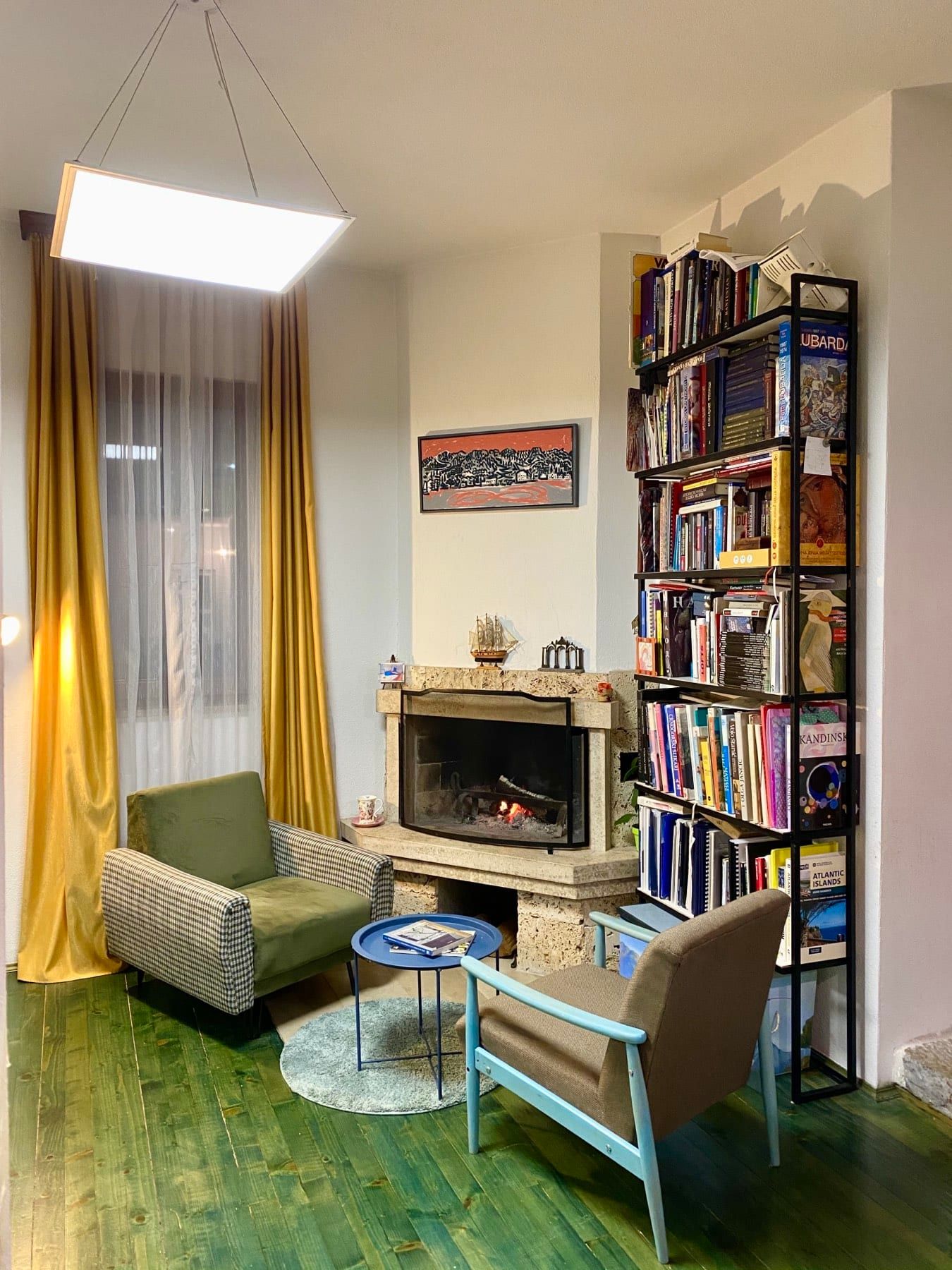 Cozy living room with a fireplace, armchairs, and shelving in a house in Shushan, Montenegro. Interior with wooden flooring.