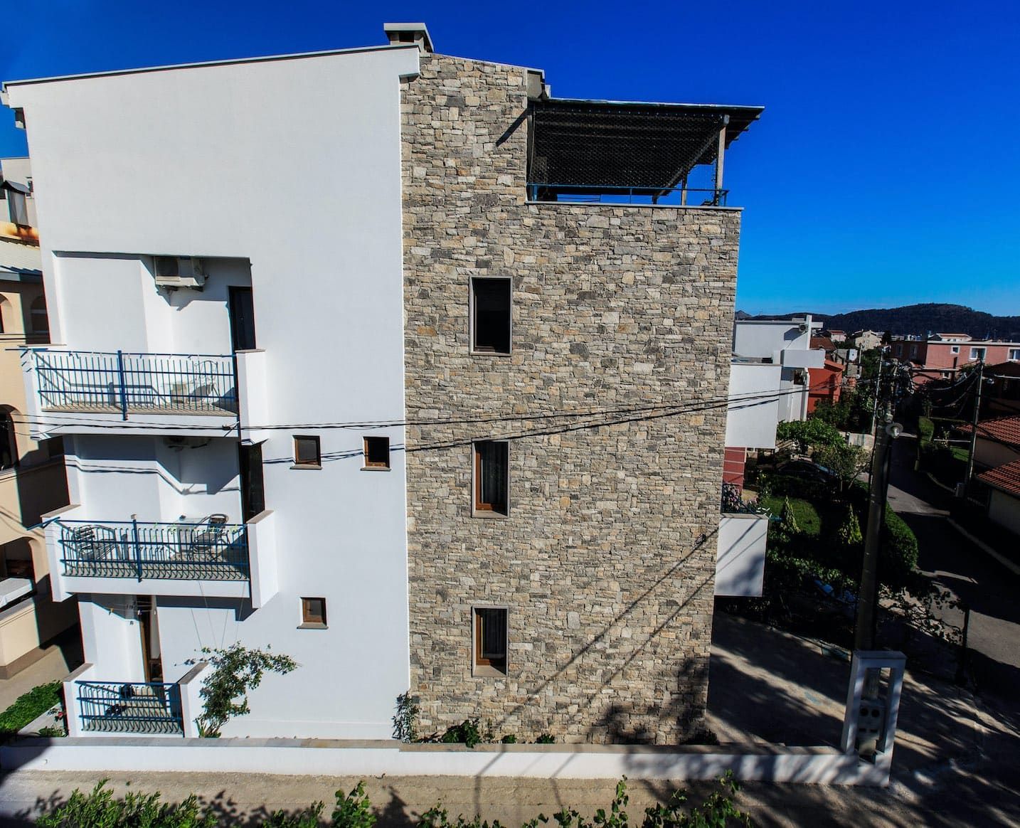 Modern house in Shushan, Montenegro: facade with stone cladding, white walls, and open terraces with a view.
