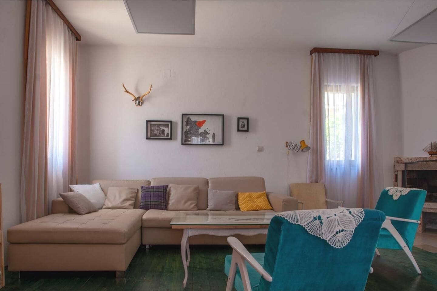 Cozy living room with a beige sofa and turquoise armchairs in a house, Shushan, Montenegro. Interior with a fireplace and decor.