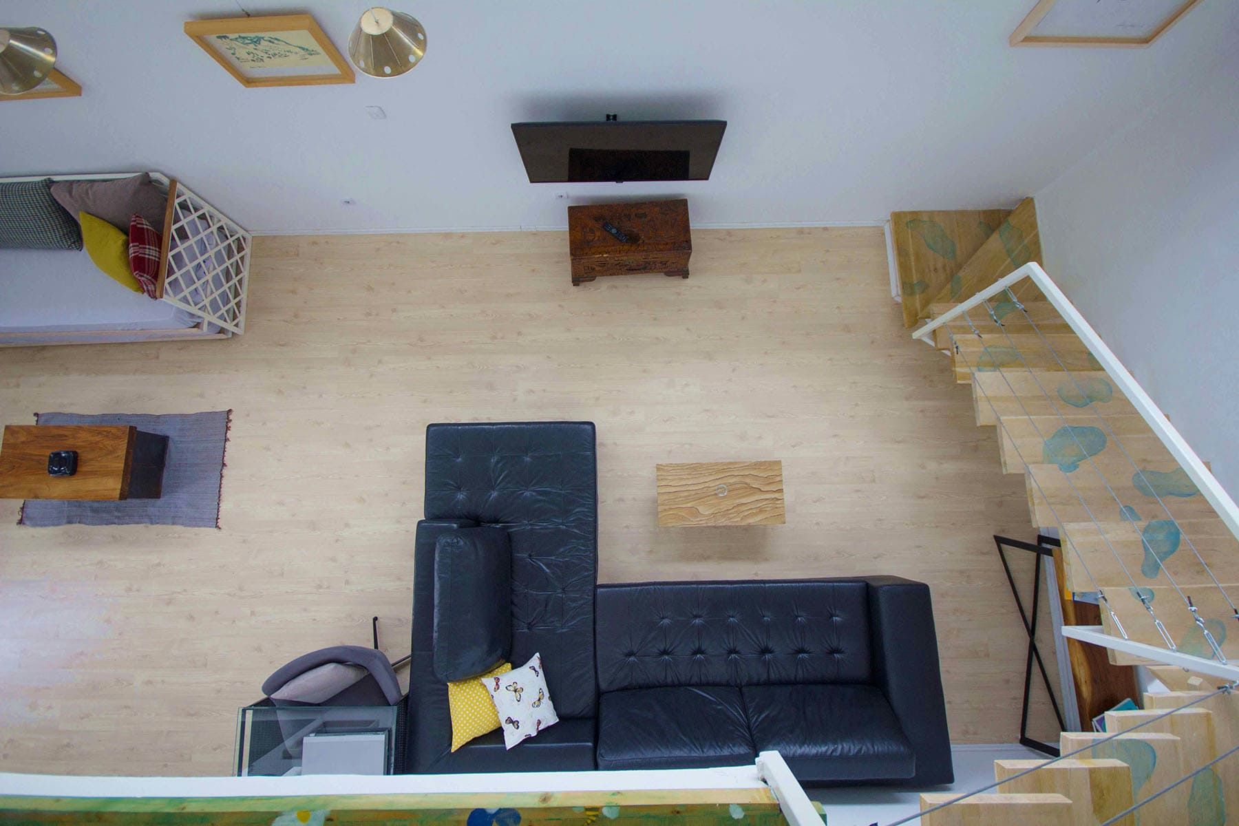 Top view of a house living room in Shushan, Montenegro: leather sofa, wooden staircase, and modern finishes.