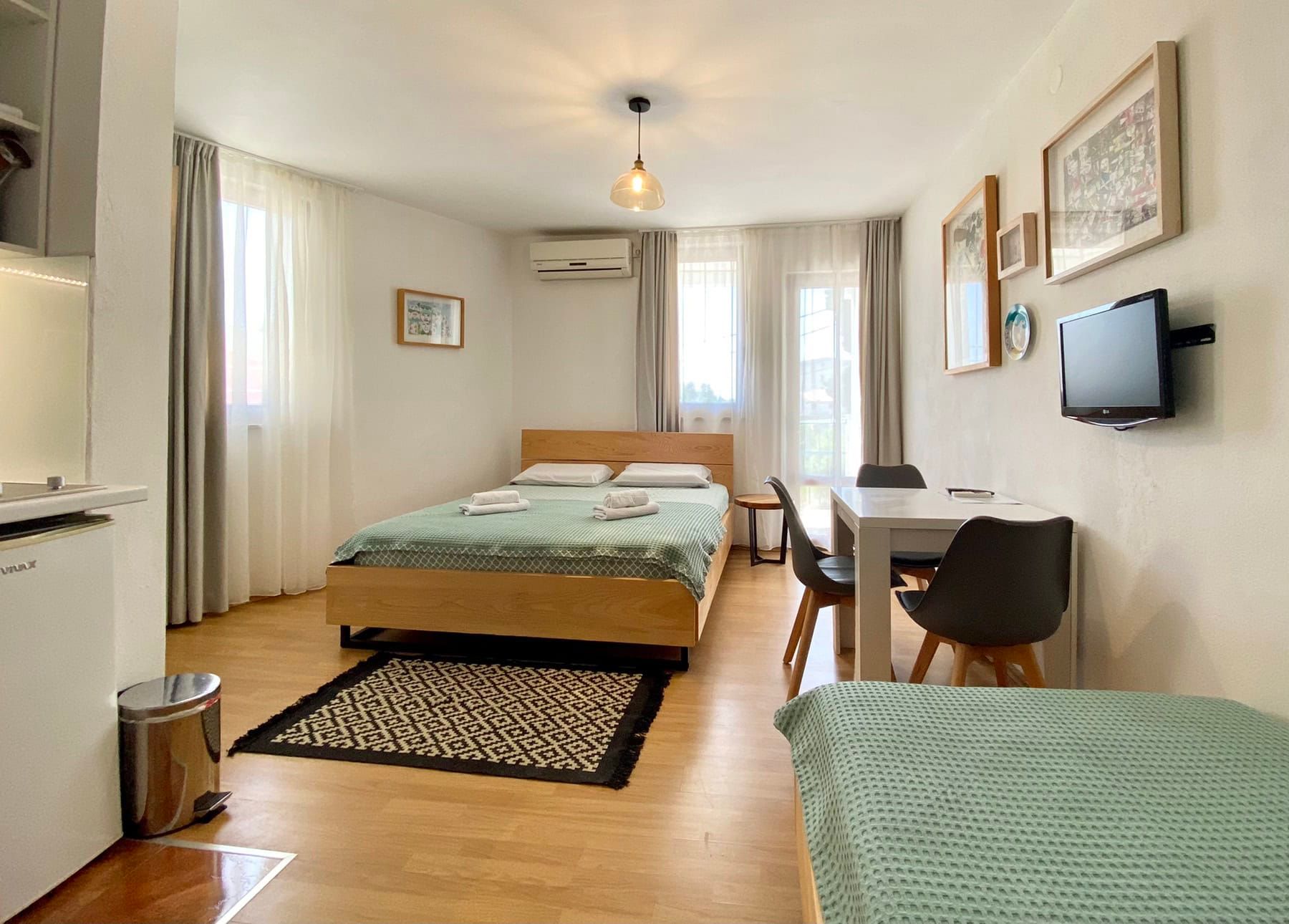 Bright bedroom in a house in Shushan, Montenegro: double bed, dining area, TV, and access to the balcony.