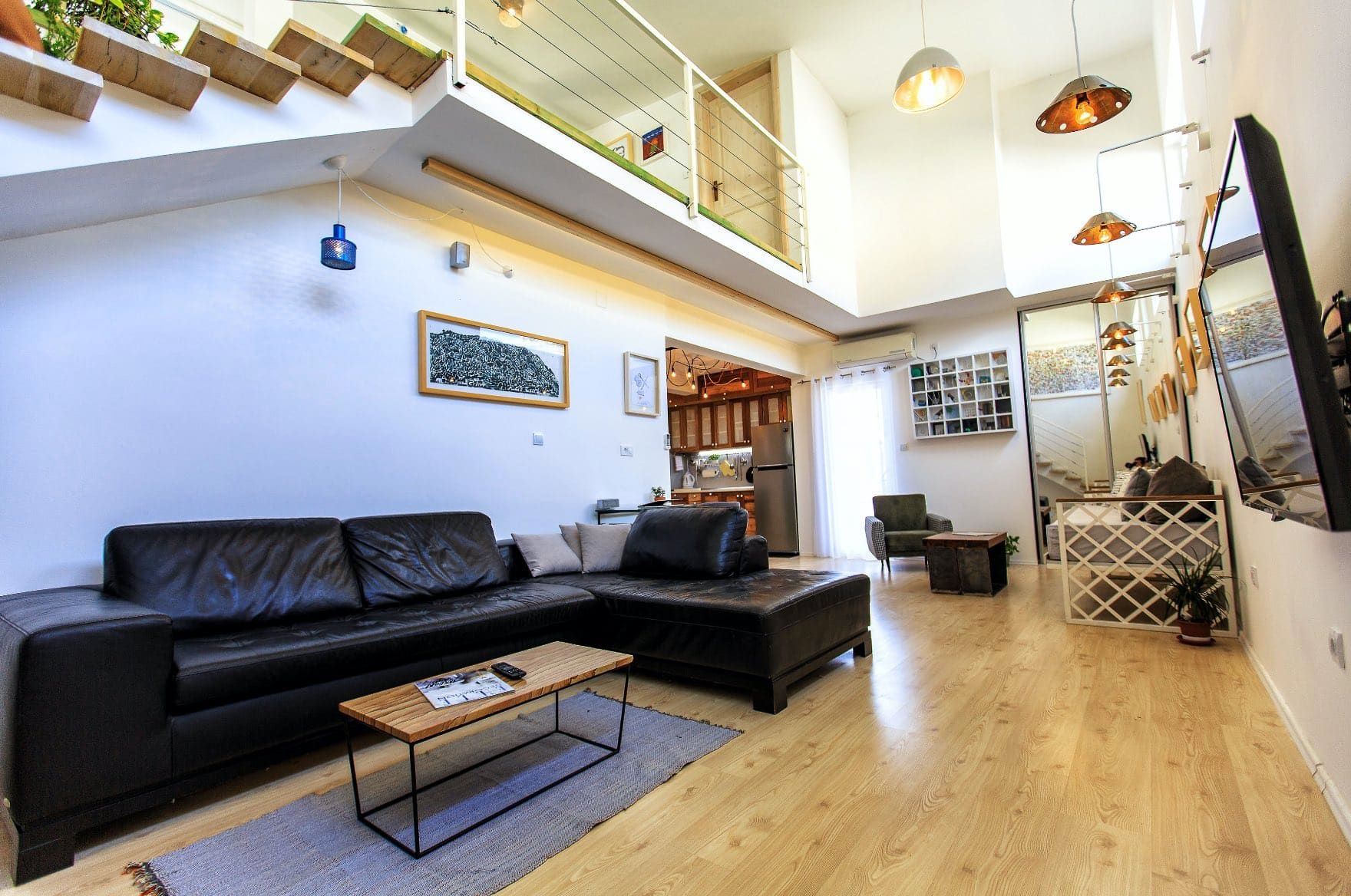 Living room in a house in Shushan, Montenegro: leather sofa, light flooring, double-height ceiling, and staircase to the second floor.