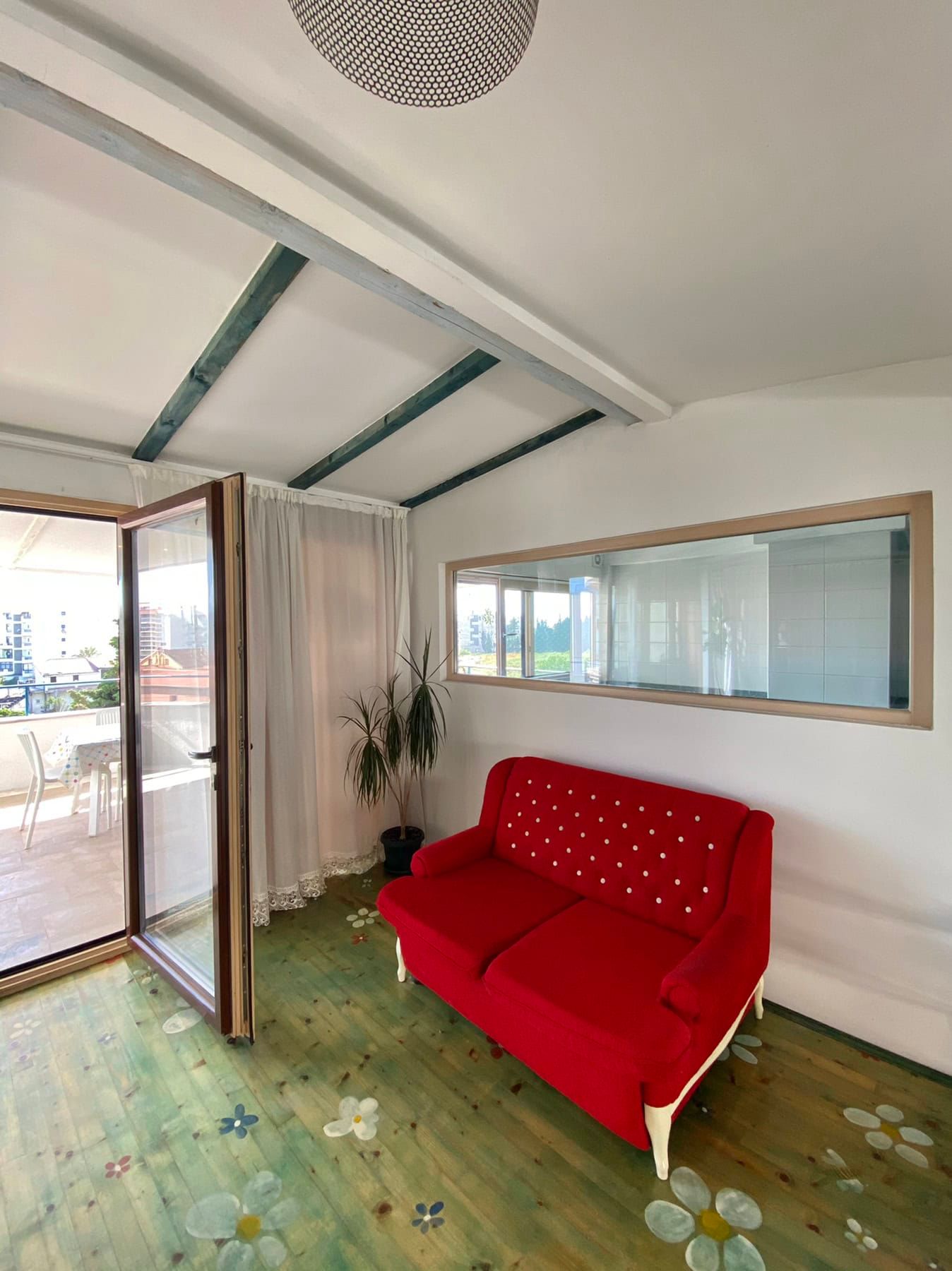 Living room with a red sofa, wooden floor, and access to the terrace in a house, Shushan, Montenegro.