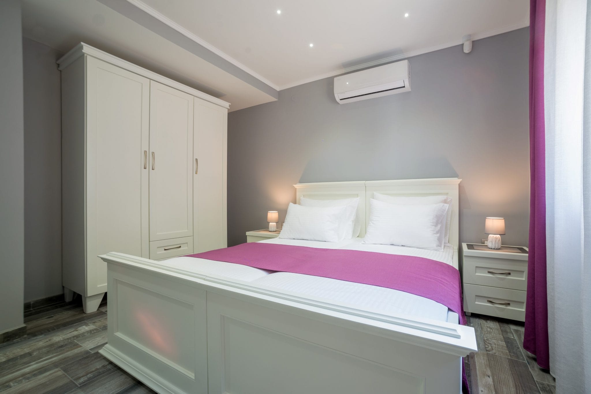 Bedroom with white furniture and a double bed in a villa in Stoliv, Montenegro. Modern interior with air conditioning.