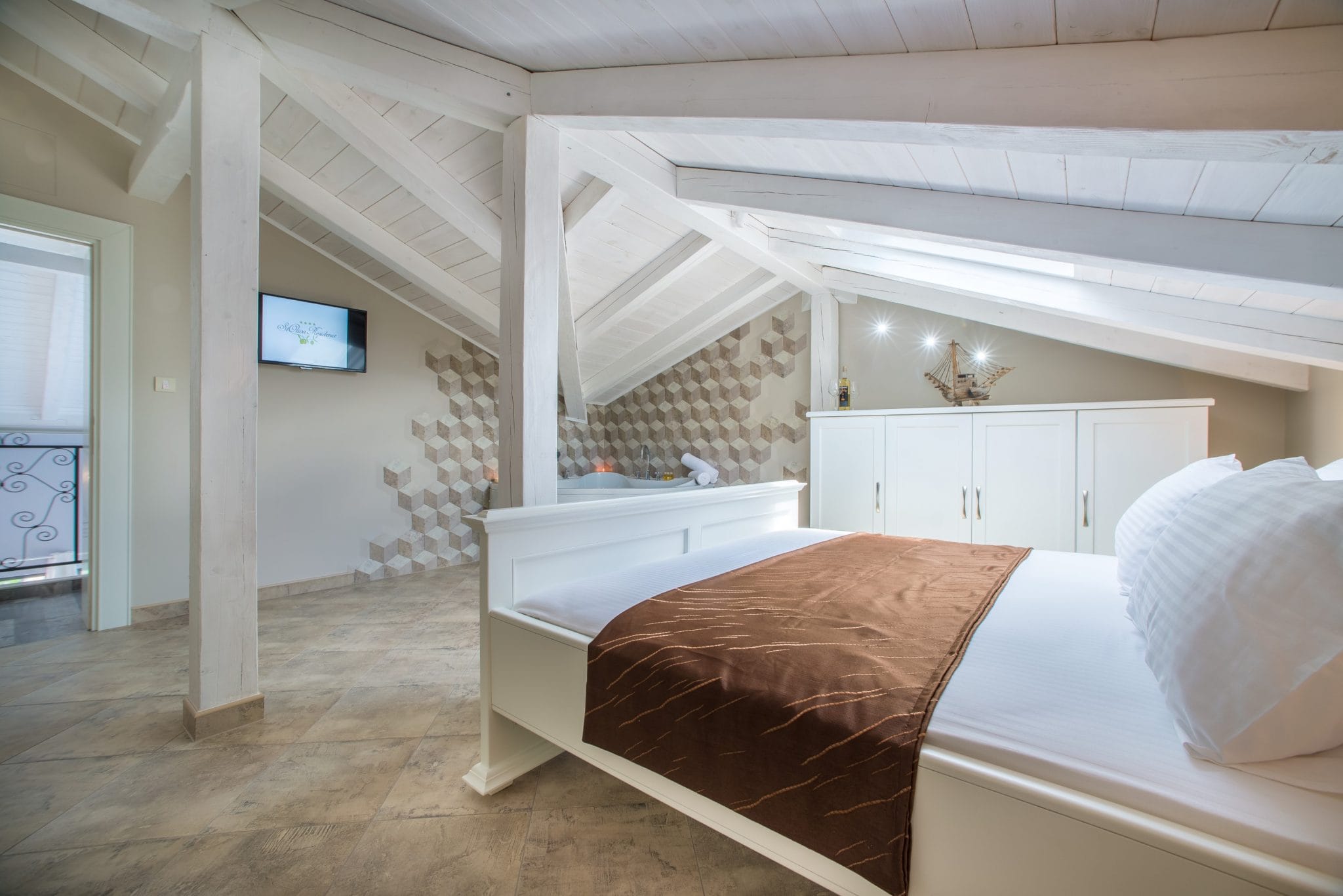 Attic bedroom in a villa in Stoliv, Montenegro: white furniture, a double bed, a jacuzzi, and tiled finishes.