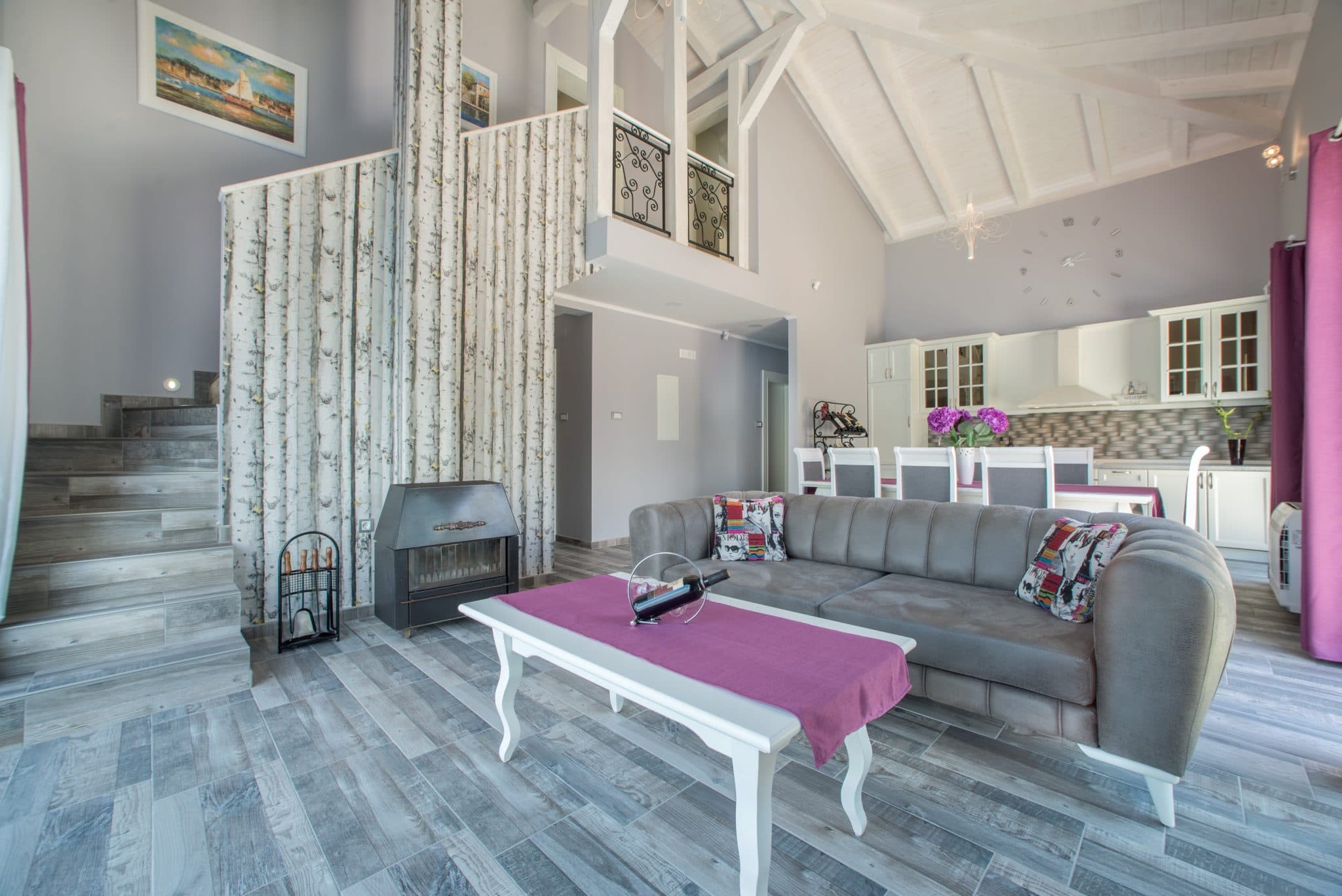 Living room with a fireplace and double-height ceiling in a villa in Stoliv, Montenegro: stylish interior with soft seating and kitchen.