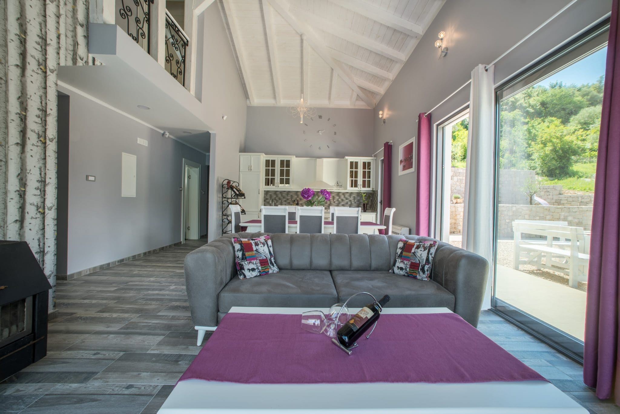 Living room with panoramic windows and kitchen in a villa in Stoliv, Montenegro: modern interior, fireplace, and terrace.