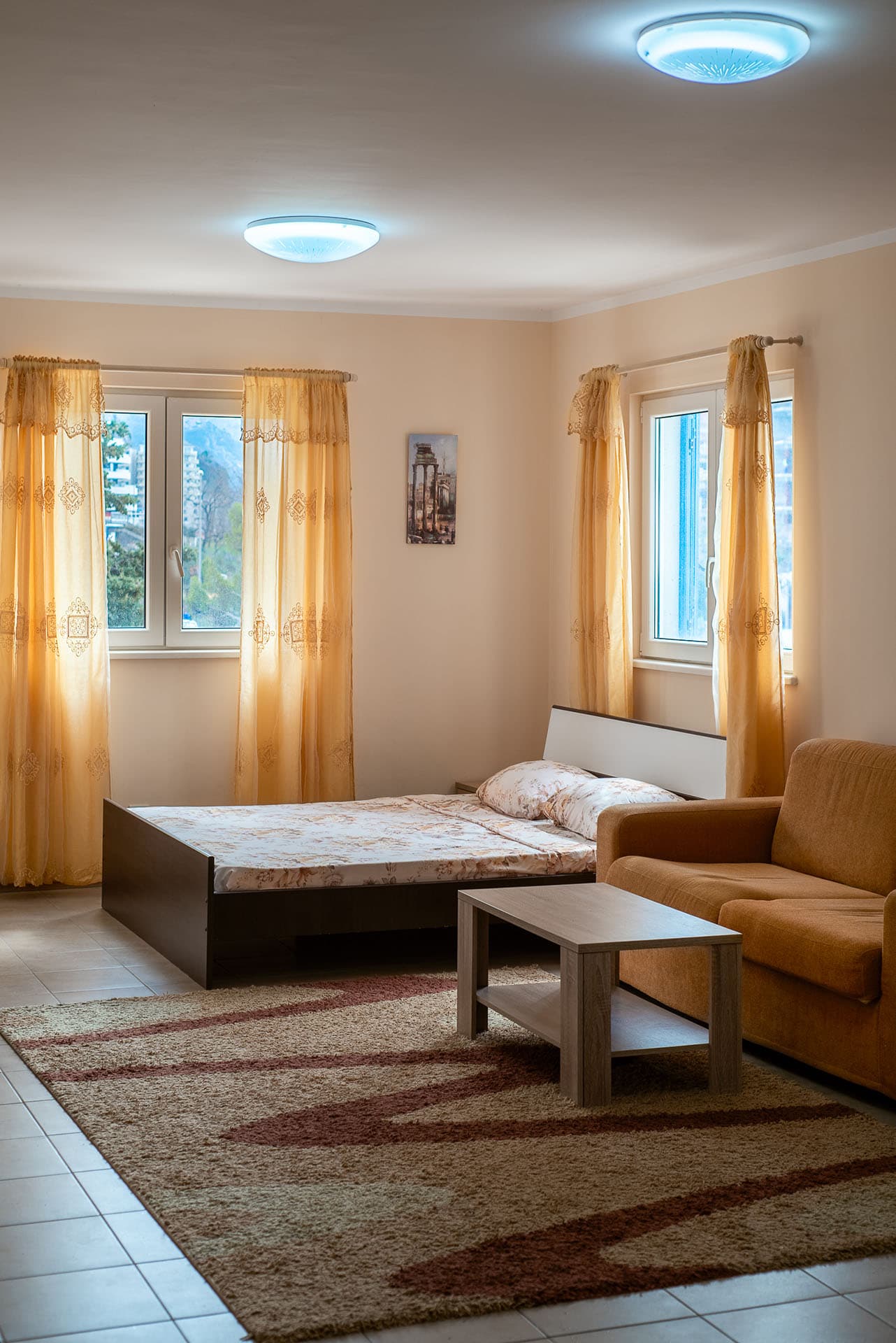Bedroom in an apartment in Bečići, Montenegro: a double bed, a soft sofa, a coffee table, and a view from the window.