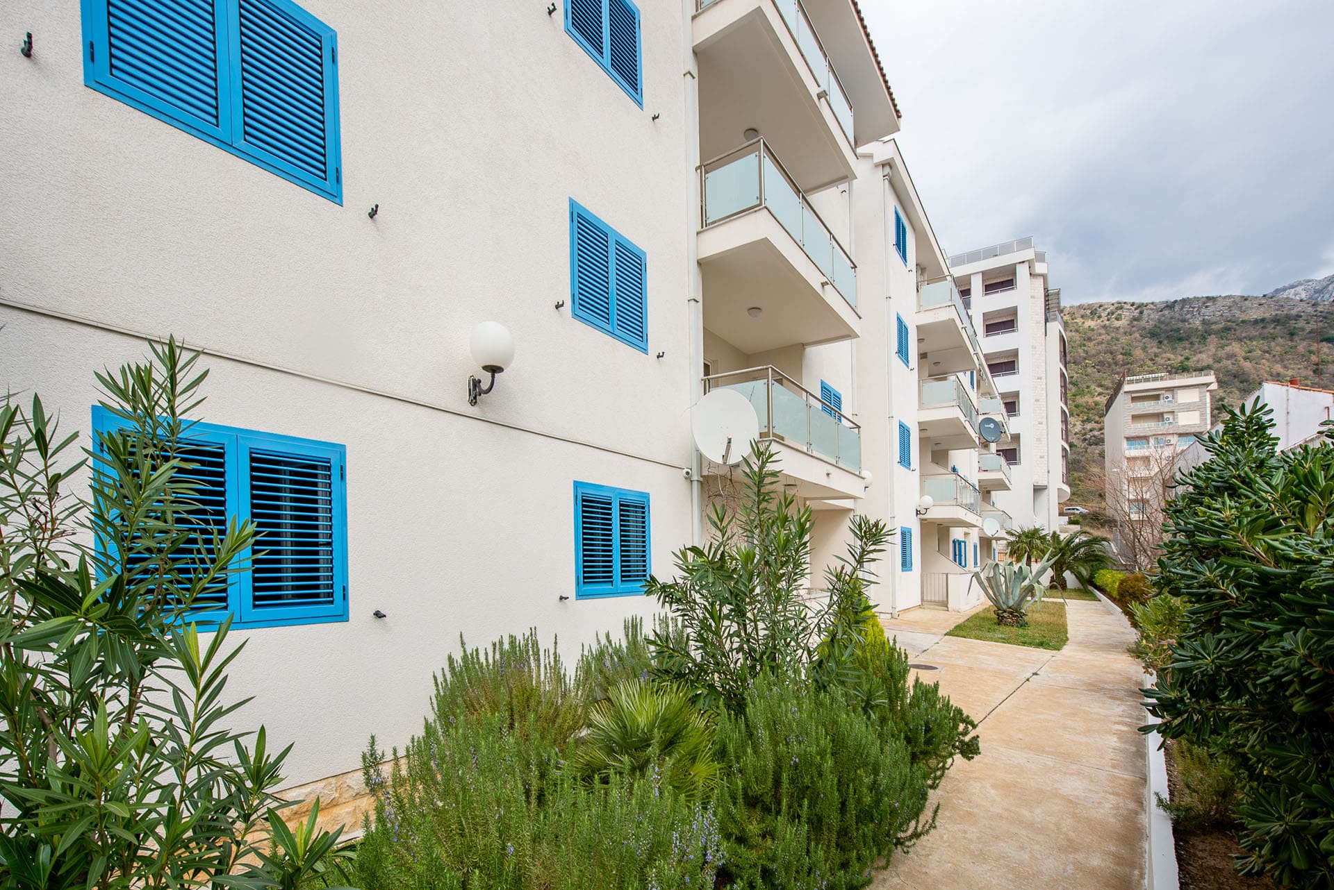 Facade of a modern residential building with blue shutters and balconies in Bečići, Montenegro, view of the courtyard area.