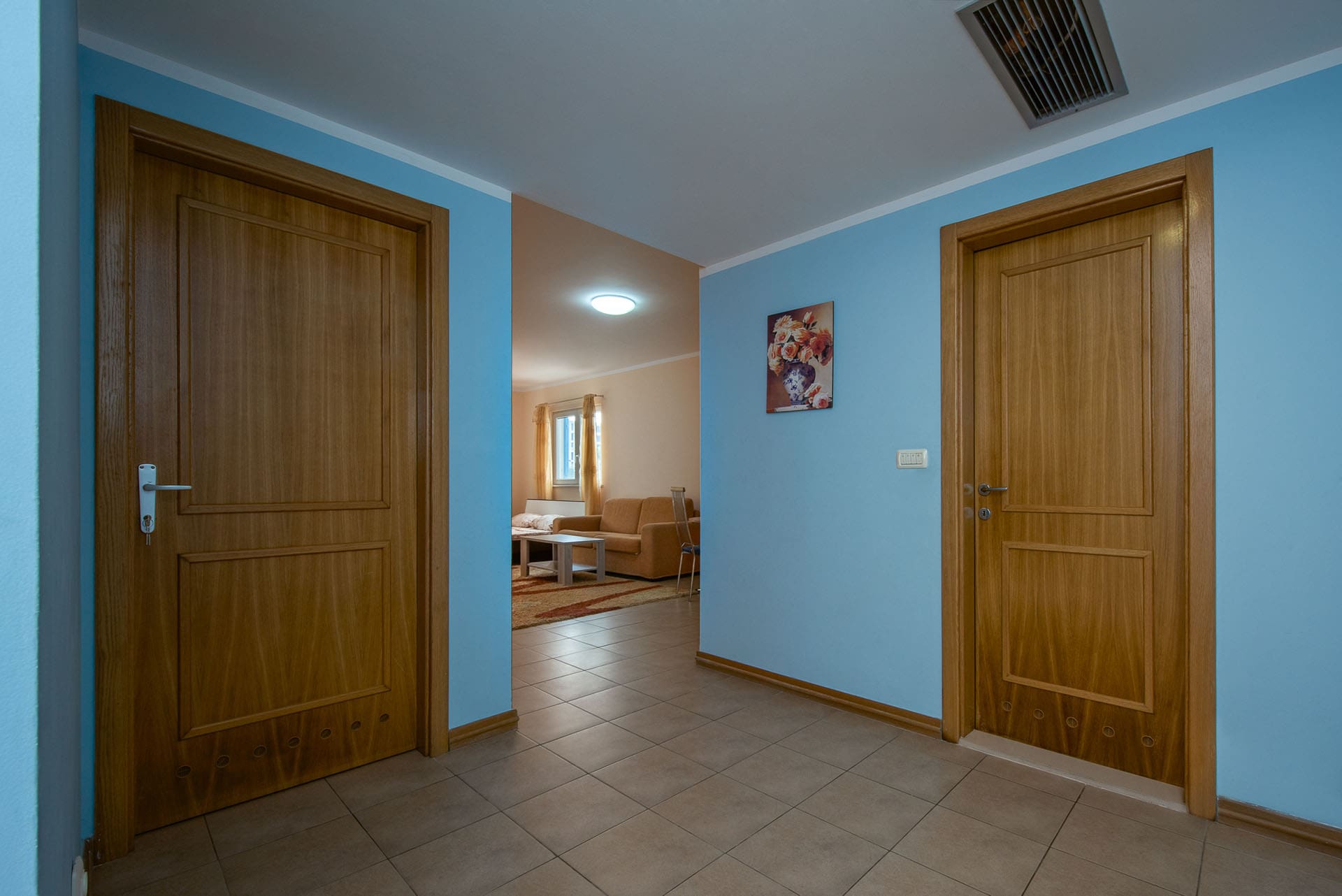 Hallway with blue walls and wooden doors in an apartment, Becici, Montenegro, view of the living room with furniture.