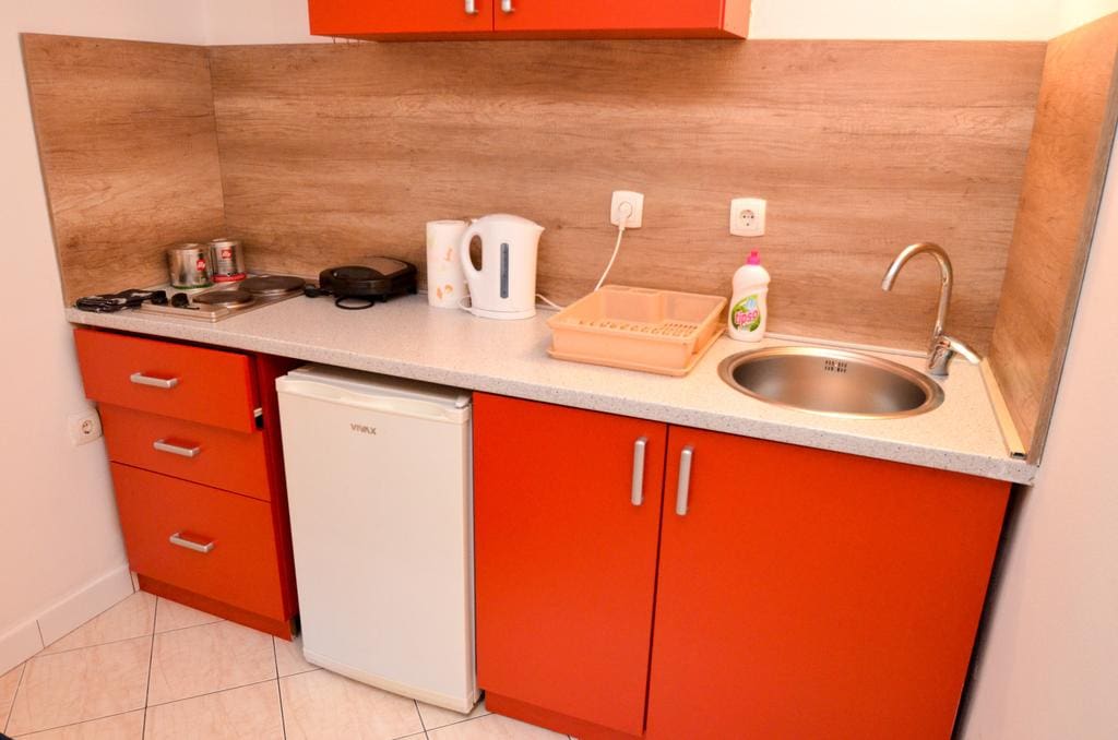 Compact kitchen with orange cabinets and appliances in an apartment, Kotor, Montenegro.