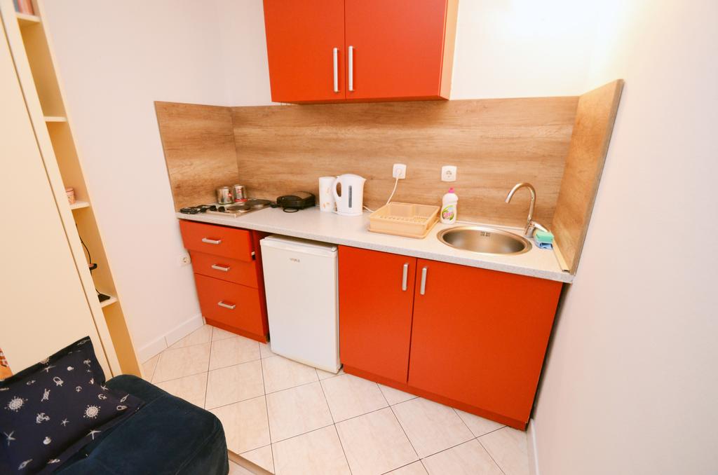 Compact kitchen with orange cabinet fronts and built-in appliances in an apartment, Kotor, Montenegro.