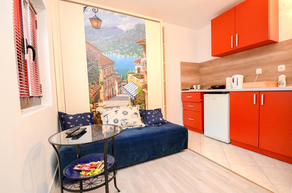 Living room with a bright kitchen and sofa in a house in Kotor, Montenegro: modern interior with photo wallpaper and a seating area.