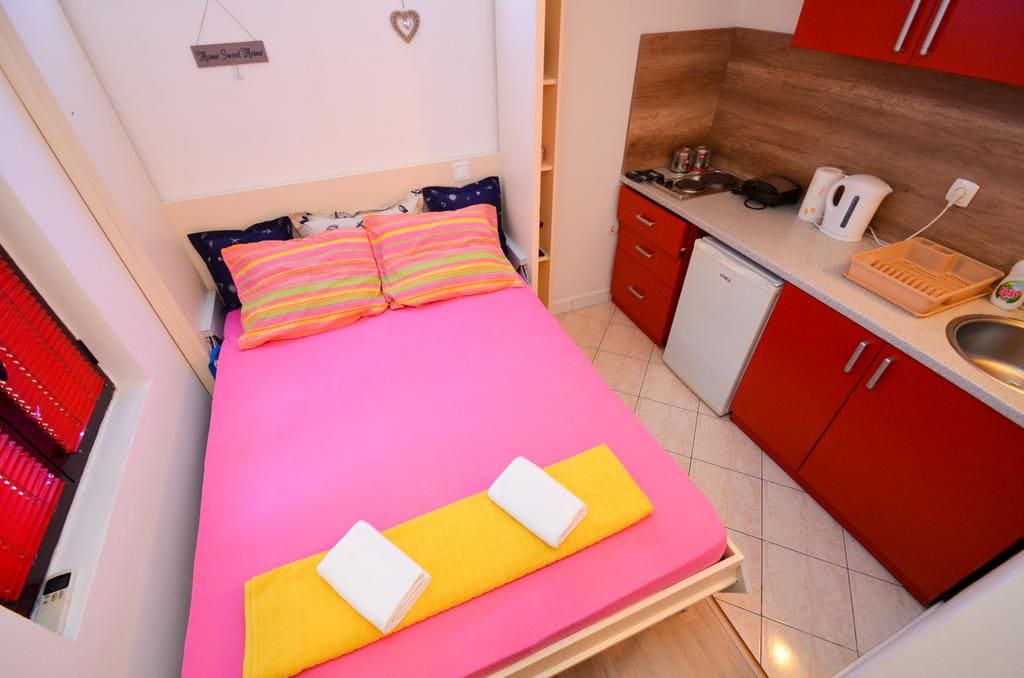 Compact bedroom with a double bed and built-in kitchen in an apartment, Kotor, Montenegro.