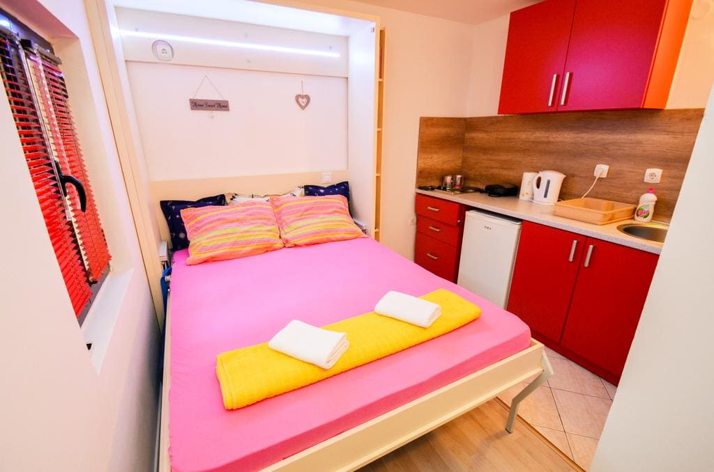 Bedroom with a double bed and kitchenette in a house in Kotor, Montenegro. Modern interior with red furniture.