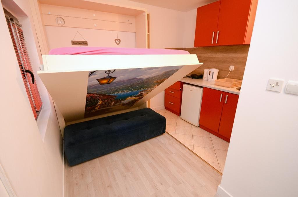 Compact bedroom with a fold-down bed and kitchenette in a house in Kotor, Montenegro. Modern finishes and furniture.