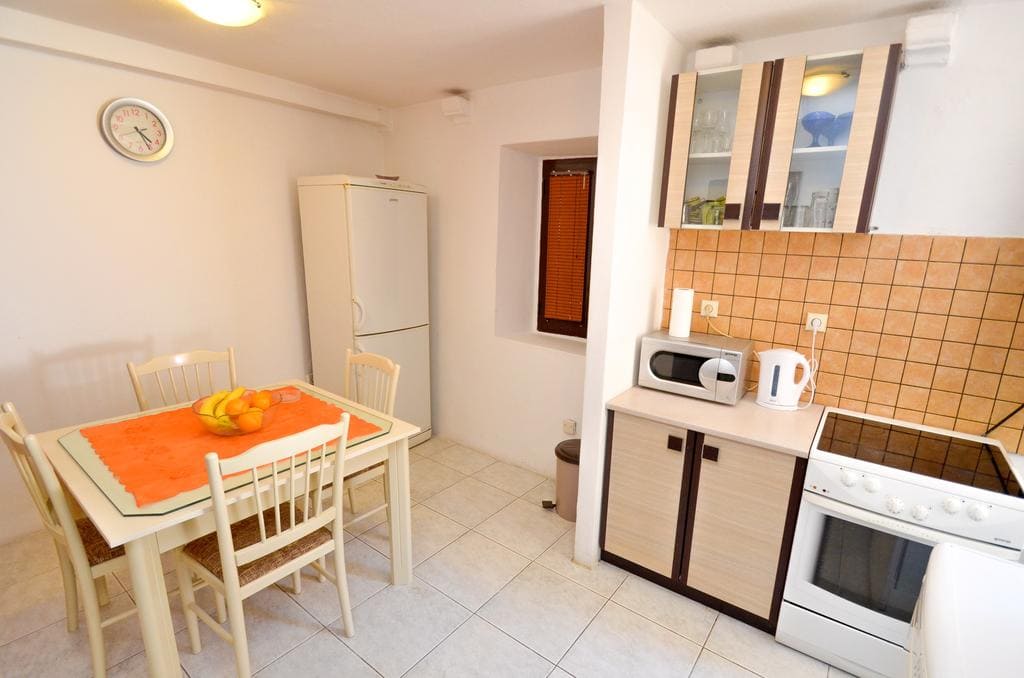 Bright kitchen-dining room in a house in Kotor, Montenegro: dining area, kitchen set, stove, and appliances.