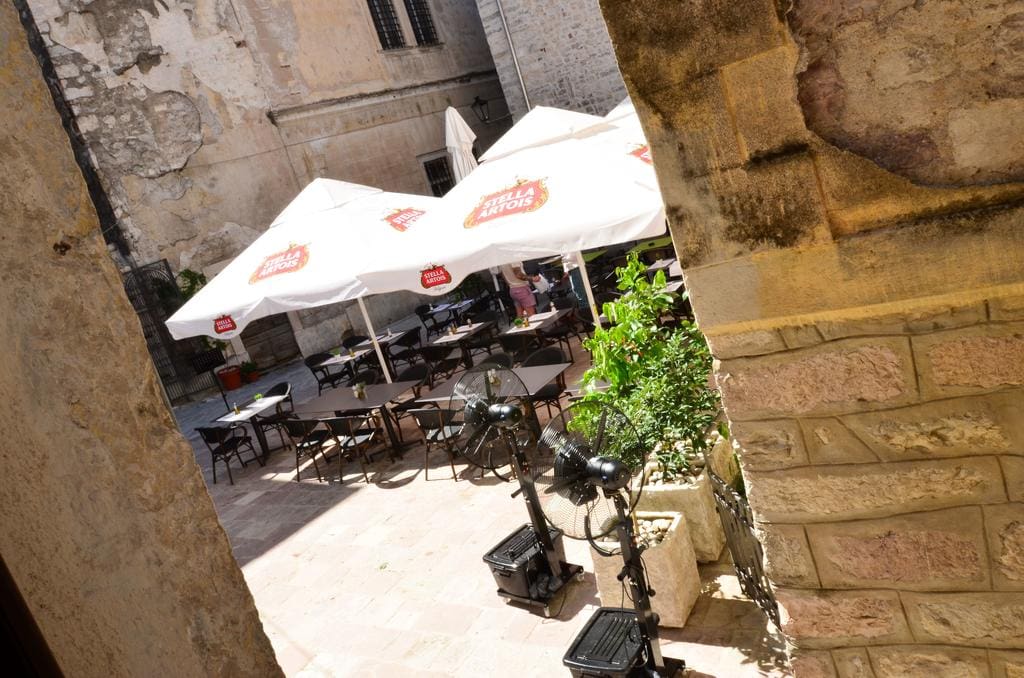Cozy restaurant terrace in the old town of Kotor, Montenegro: tables under umbrellas and stone architecture of the buildings.