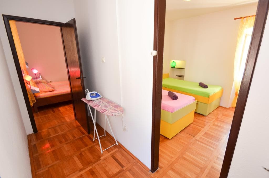 Two bedrooms with single beds and parquet flooring in a house in Kotor, Montenegro. Cozy interior with an ironing board.