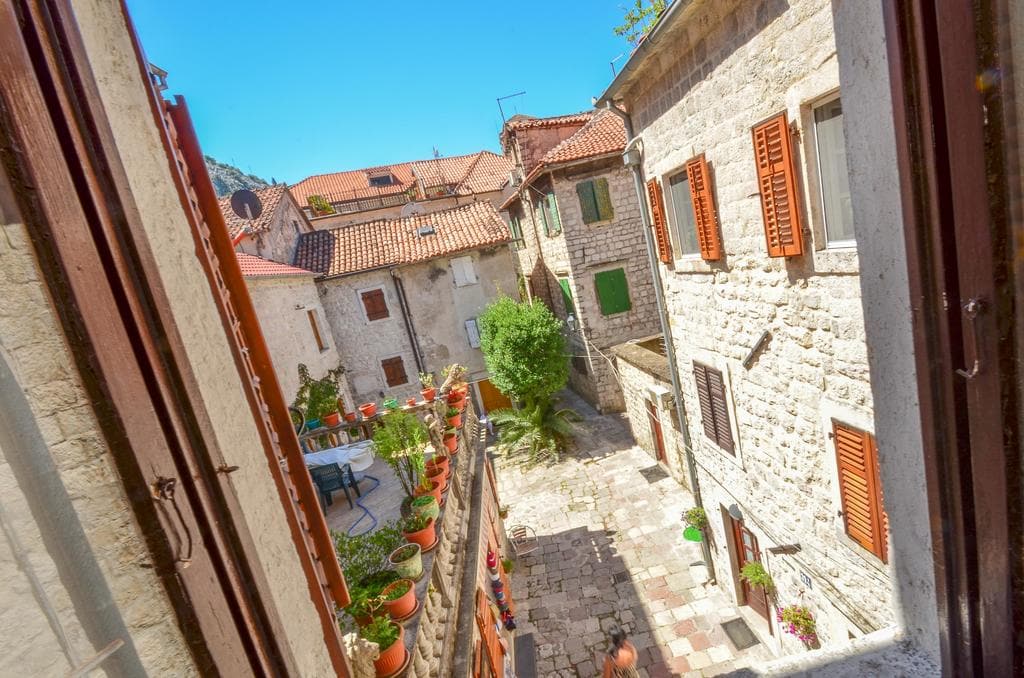 View from the window of a cozy stone courtyard and old houses with tiled roofs in the Old Town of Kotor, Montenegro.