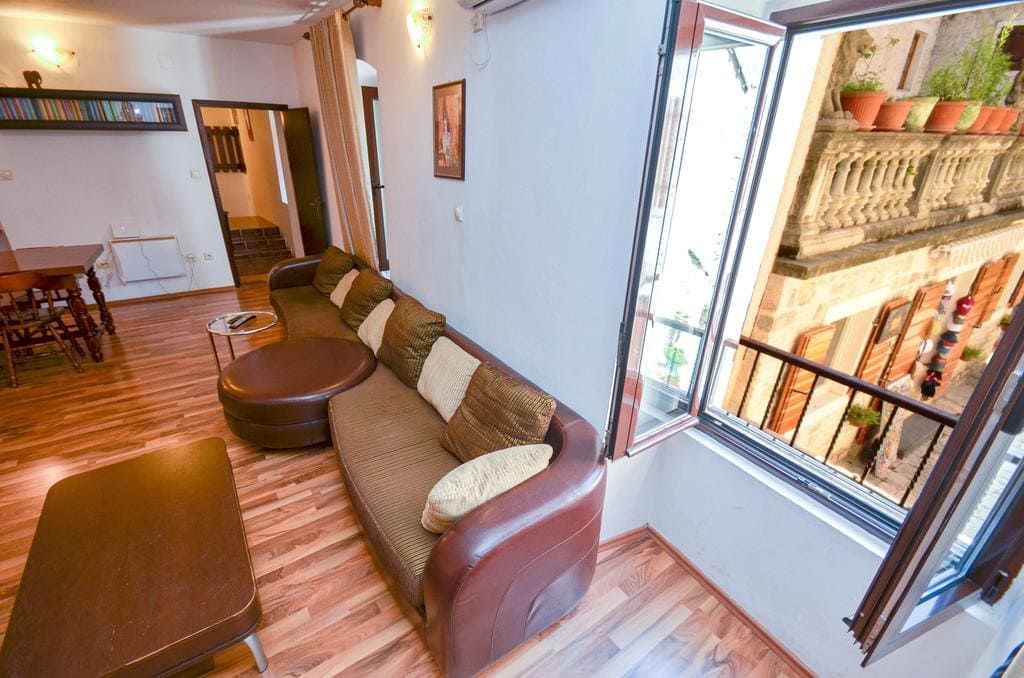 Living room with a leather sofa and a view of the old town in a house in Kotor, Montenegro: interior with wooden flooring.