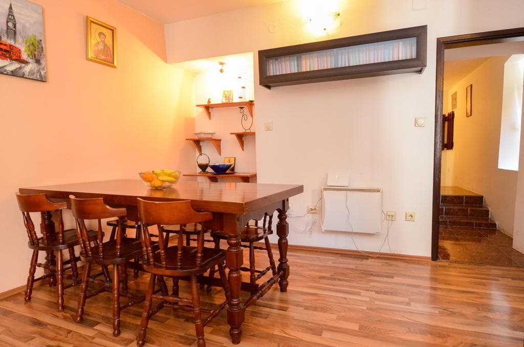 Living room with a wooden dining table and chairs in a house in Kotor, Montenegro: interior with shelves and decor.