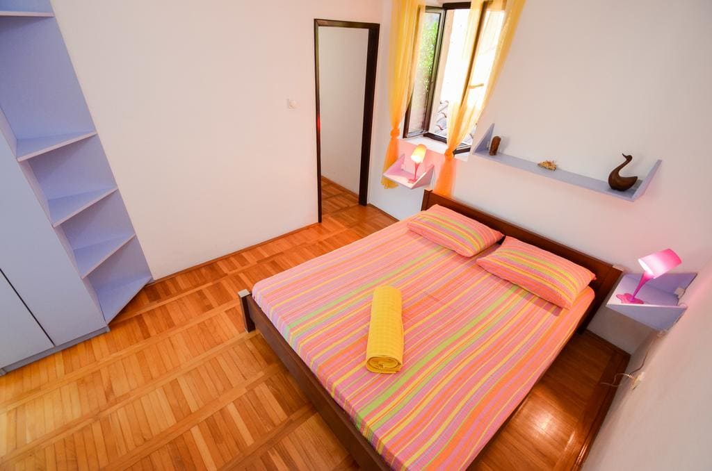 Bedroom with a double bed, parquet flooring, and a bright interior in a house for sale, Kotor, Montenegro.